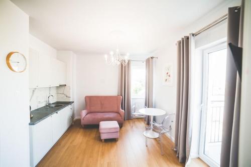 un salon avec une chaise rose et une table dans l'établissement Apartament Słoneczny, à Uniejów
