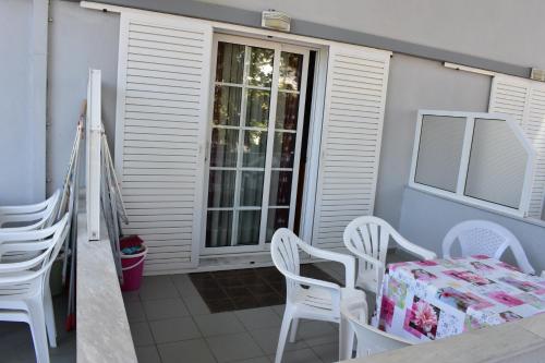 a patio with white chairs and a table with a box at Galanis Studios and Apartments in Platamonas