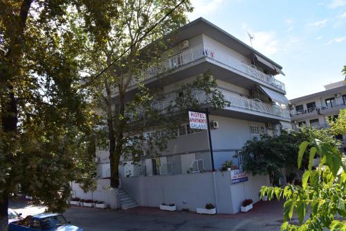 a white apartment building with a sign in front of it at Galanis Studios and Apartments in Platamonas