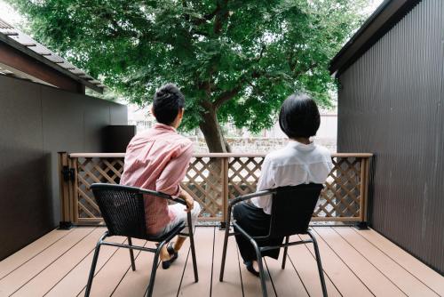 a man and woman sitting in chairs on a deck at Asanogawa 旅音 in Kanazawa