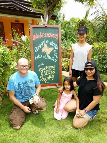 a group of people sitting on the grass in front of a sign at Chekesh Casa in Siquijor