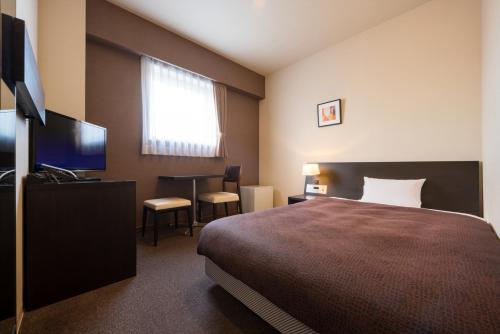 a hotel room with a bed and a flat screen tv at Montein Hotel in Kitakami