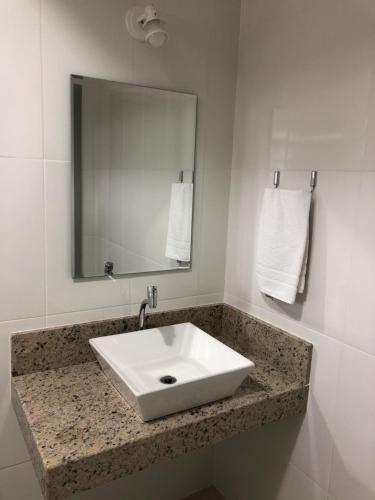 a bathroom with a white sink and a mirror at JP Palace Hotel in Saquarema