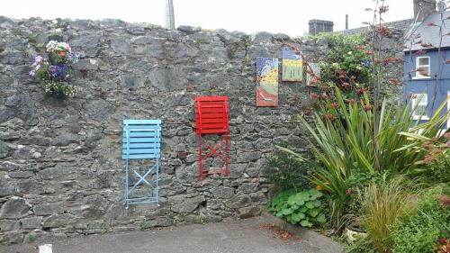 two colorful chairs sitting on a stone wall at An Stór Townhouse in Midleton