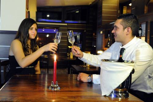 a man and woman sitting at a table with wine glasses at Complex Cochet in Buşteni