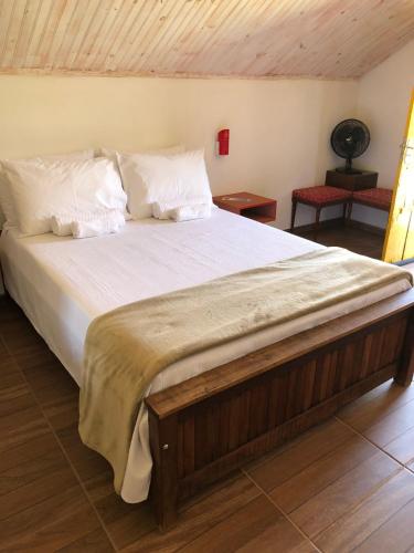 a large bed with white sheets and pillows at João e Maria Restaurante e Chalés in Tiradentes