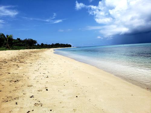 a sandy beach with a cloudy sky and the ocean at Paraiso Beach Hotel in Big Corn Island