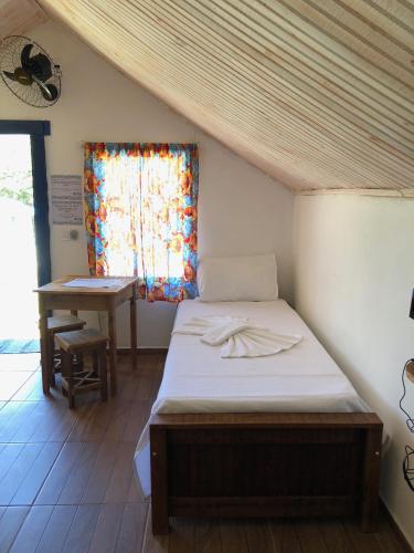 a bed in a room with a window and a table at João e Maria Restaurante e Chalés in Tiradentes