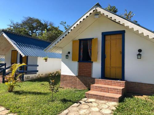 a small white house with a yellow door at João e Maria Restaurante e Chalés in Tiradentes