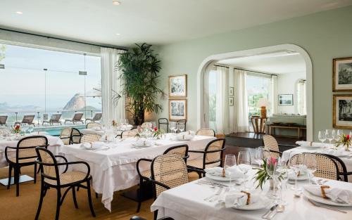a dining room with white tables and chairs and a large window at Vila Santa Teresa in Rio de Janeiro