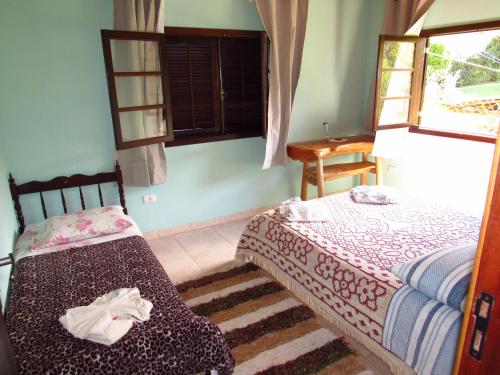 um quarto com 2 camas e uma janela em Chalé Caminho Das Cachoeiras em Visconde de Mauá