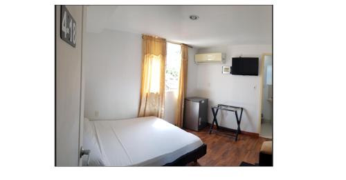 Hotel Jardin De Tequendama في كالي: غرفة نوم بسرير ابيض ونافذة