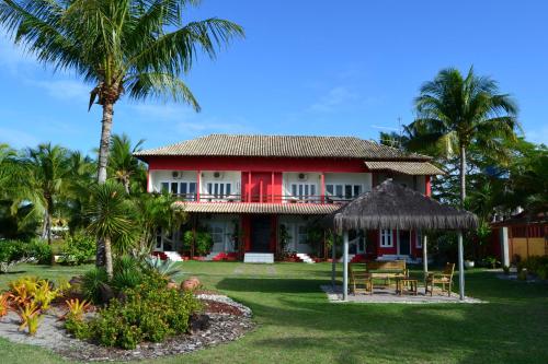 a large white house with trees and palm trees at Pousada Corumbau in Corumbau