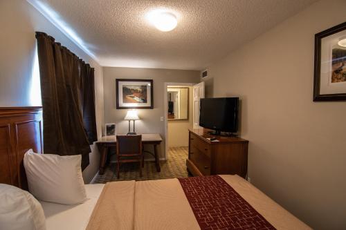 een hotelkamer met een bed en een bureau met een televisie bij The Crow Peak Lodge in Spearfish