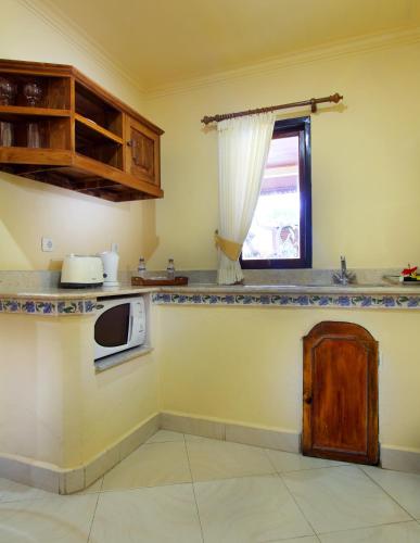 a kitchen with a counter with a microwave and a window at Bali Seascape Beach Club in Candidasa