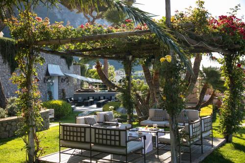 a patio with chairs and tables under a pergola at Villa Marina Capri in Capri