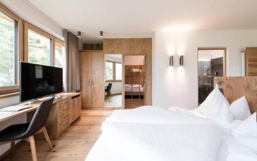 Schlafzimmer mit einem Bett, einem Schreibtisch und einem TV in der Unterkunft Hotel Gasserhof in Brixen