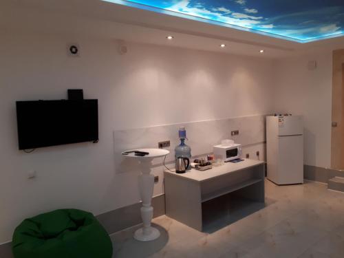 a living room with a tv and a table and a refrigerator at Park Puscha Sauna Deluxe Apartment & Terrace in Kyiv