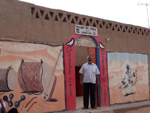 a man standing in front of a door with a sign at Auberge Gitelkst in Tafraoute