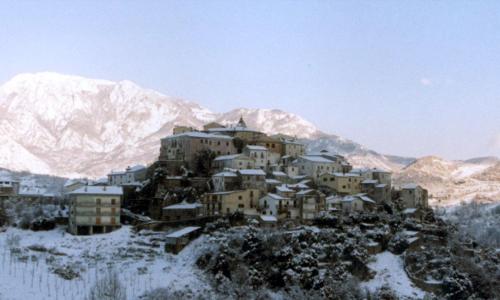 un groupe de bâtiments sur une colline avec des montagnes enneigées dans l'établissement Residenza Vallefiorita, à Rocchetta a Volturno