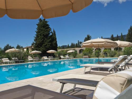 a swimming pool with chairs and umbrellas in a resort at Hotel-Restaurant Le Moulin De La Camandoule in Fayence