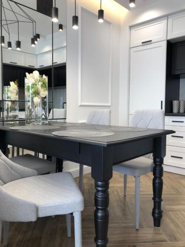 a dining room with a black table and chairs at Family & Business Sauna Apartments No1 Leśny nad Zalewem Cedzyna Unikat - 3 Bedroom with Private Sauna, Bath with Hydromassage, Terrace, Garage, Catering Options in Kielce