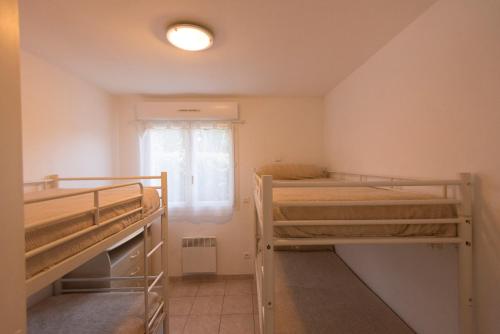 a room with two bunk beds and a window at Residence de tourisme Le clos des Vendanges in Moriani Plage