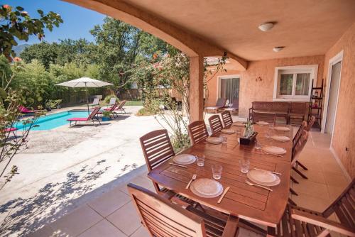 a dining room with a table and chairs and a pool at Residence de tourisme Le clos des Vendanges in Moriani Plage