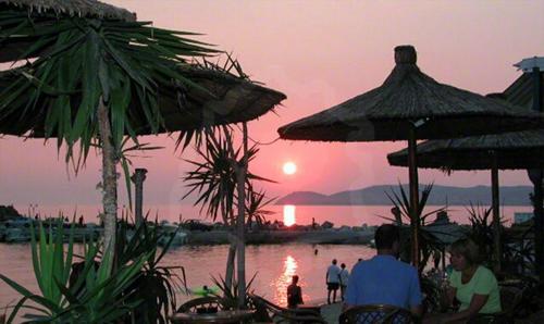 a group of people sitting under umbrellas at a beach at Sunsets in Thassos 2 in Skala Sotiros