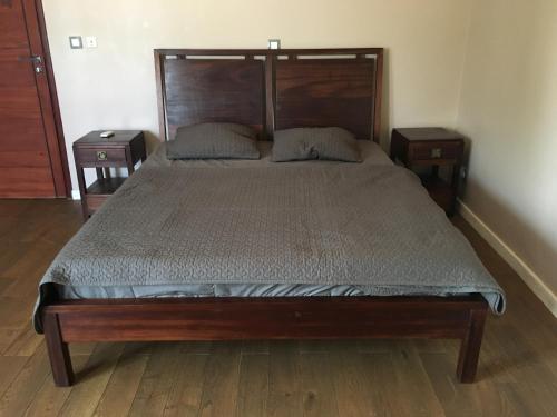 a bedroom with a large wooden bed with two night stands at Apries de Sais - villa de standing avec piscine in Aogan