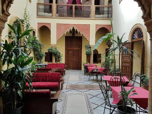 un restaurante con sofás rojos, mesas y plantas en Riad Marlinea, en Sale