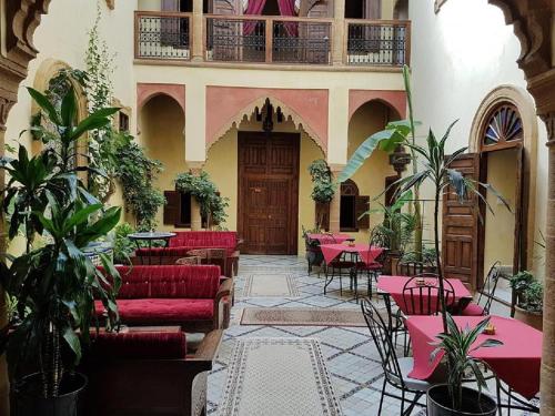um restaurante com sofás vermelhos, mesas e plantas em Riad Marlinea em Salé