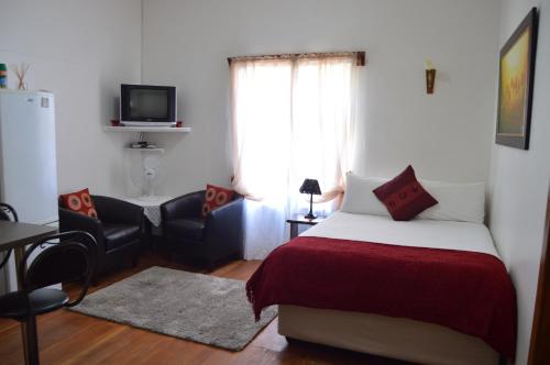 a bedroom with a bed and a chair and a television at Villelodge Accommodation in Lüderitz