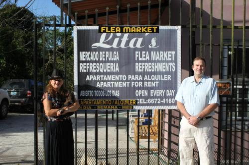 a man and a woman standing in front of a sign at Lita's Place in Cordillera Arriba