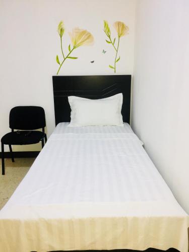 a bedroom with a white bed and a chair at La Fortuna Roja in San José