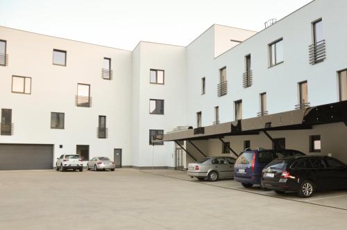 a large white building with cars parked in a parking lot at Rezidencia Amélia in Bardejovské Kúpele