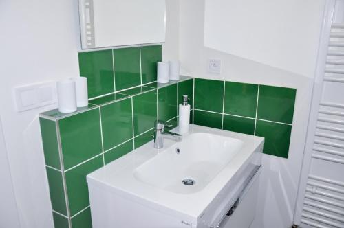 a bathroom with a sink and a green tiled wall at Rezidencia Amélia in Bardejovské Kúpele
