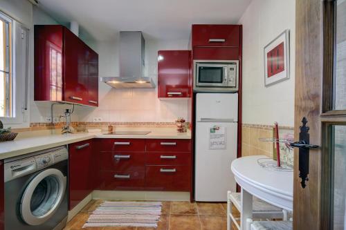 モンテハケにあるMagnífica casa con piscina privadaのキッチン(赤いキャビネット、洗濯機付)