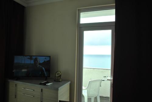 a room with a television and a window with a view of the ocean at the View Apartment in Makhinjauri