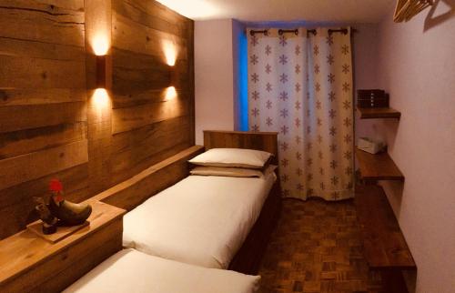 een slaapkamer met 2 bedden in een kamer met houten wanden bij La Maison de Clémence in Saint-Rhémy-en-bosses