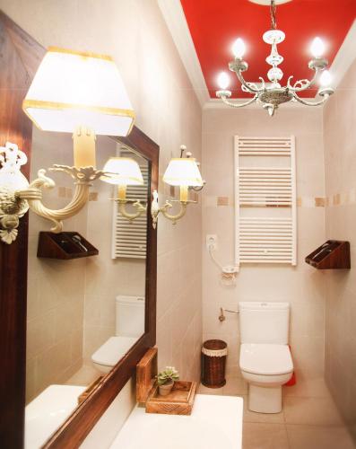 a bathroom with a mirror and a toilet and a chandelier at Apartamentos Alcoba de Baco in Barbastro