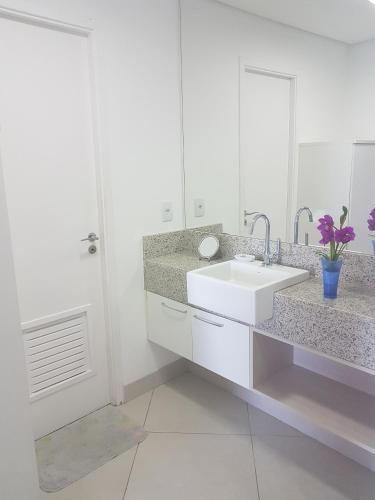 a white bathroom with a sink and a mirror at Landscape Beira mar in Fortaleza