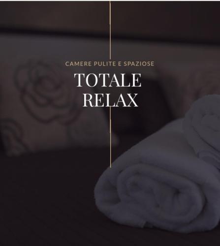 a sign that reads toale relax with a pile of towels at Beatus Suites And Rooms B&B in Canicattì