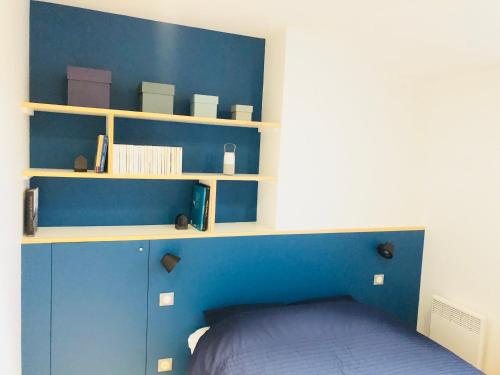 a blue bedroom with a bed and shelves at L'AppaRt in La Rochelle