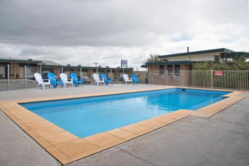 ein Pool mit blauen Stühlen und ein Gebäude in der Unterkunft Hi Way Eight Motor Inn in Stawell