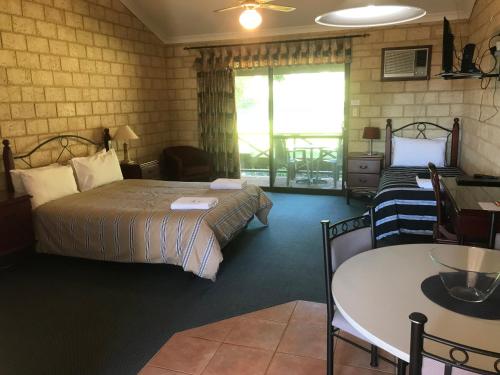 a hotel room with two beds and a table and a table and chairs at Karri Forest Motel in Pemberton