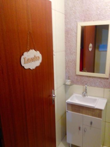 a bathroom with a wooden door and a sink at Recanto da Dani in Penha