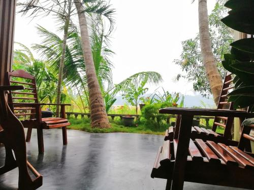 eine Veranda mit 2 Holzstühlen und Palmen in der Unterkunft Viveka Inn Guest and Yala Safari in Tissamaharama