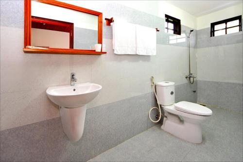 une salle de bain avec un lavabo, des toilettes et un miroir dans l'établissement Thao Nguyen Phat Homestay, à Hội An