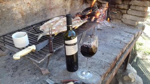 a bottle of wine and a glass next to a grill at Hotel de Montaña Estancia Niña Paula in Nono